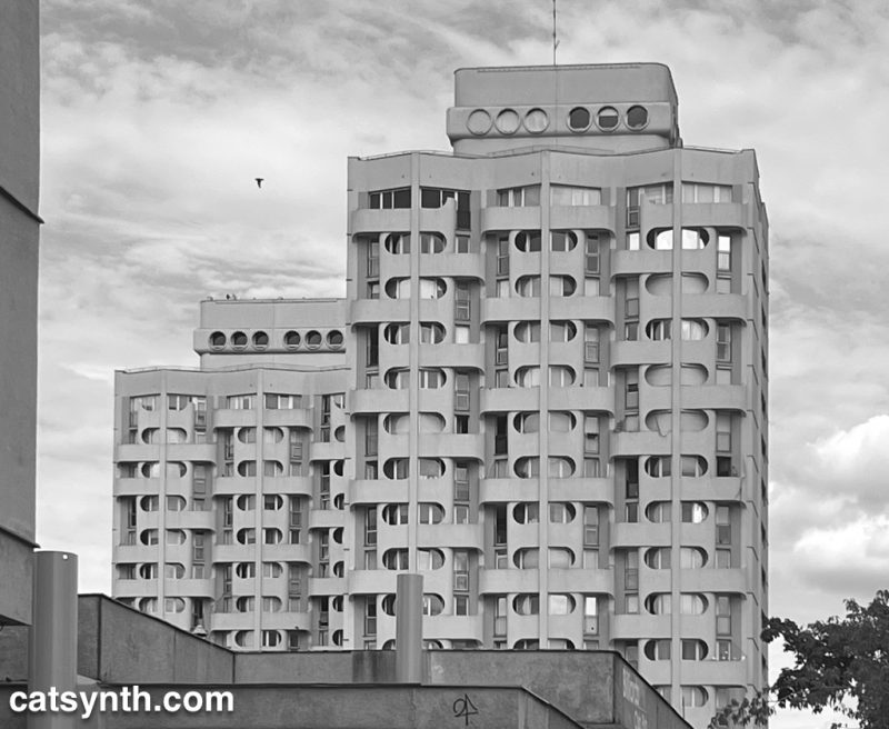 Brutalist highrise buildings with rounded windows. Dramatic clouds in the sky.