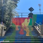 Colorful abstract mural painted on an outdoor staircase connecting parts of a city street